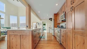 A spacious kitchen with wooden cabinets, a central island, and large windows offering a view.