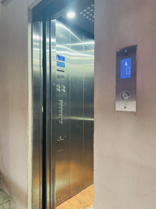 An elevator with a digital display, emergency call button, and a sign indicating OTIS elevator brand.