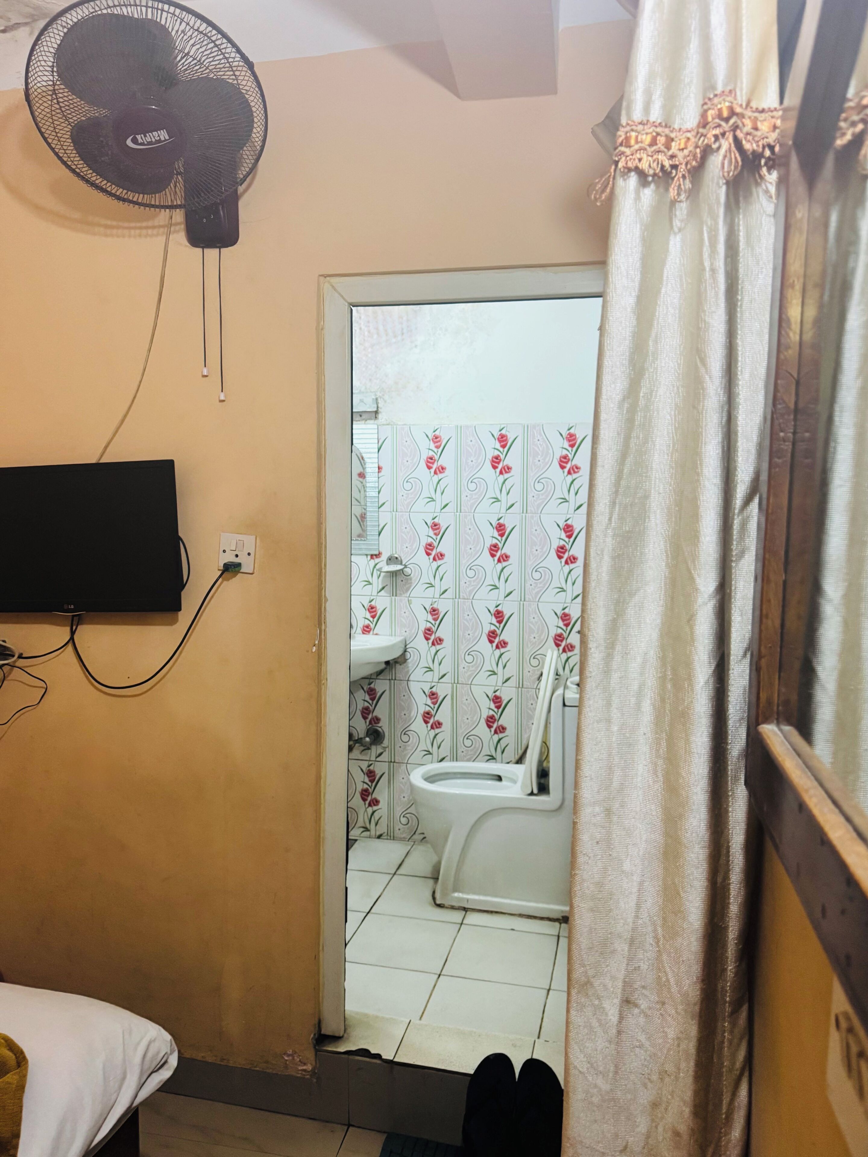 A small bathroom with a toilet, sink, and a wall-mounted fan.