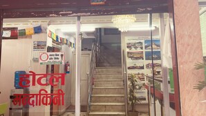 The entrance of a hotel with a staircase leading inside, a signboard with contact information, and a water dispenser outside. - Om Mandakini Hotel (Kathmandu)