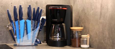 A kitchen with a Bosch coffee maker, a knife block, and a spice rack.