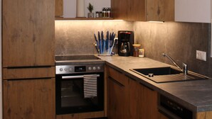 Una cuina moderna amb armaris de fusta, forn incorporat, cafetera i un rentapeus.