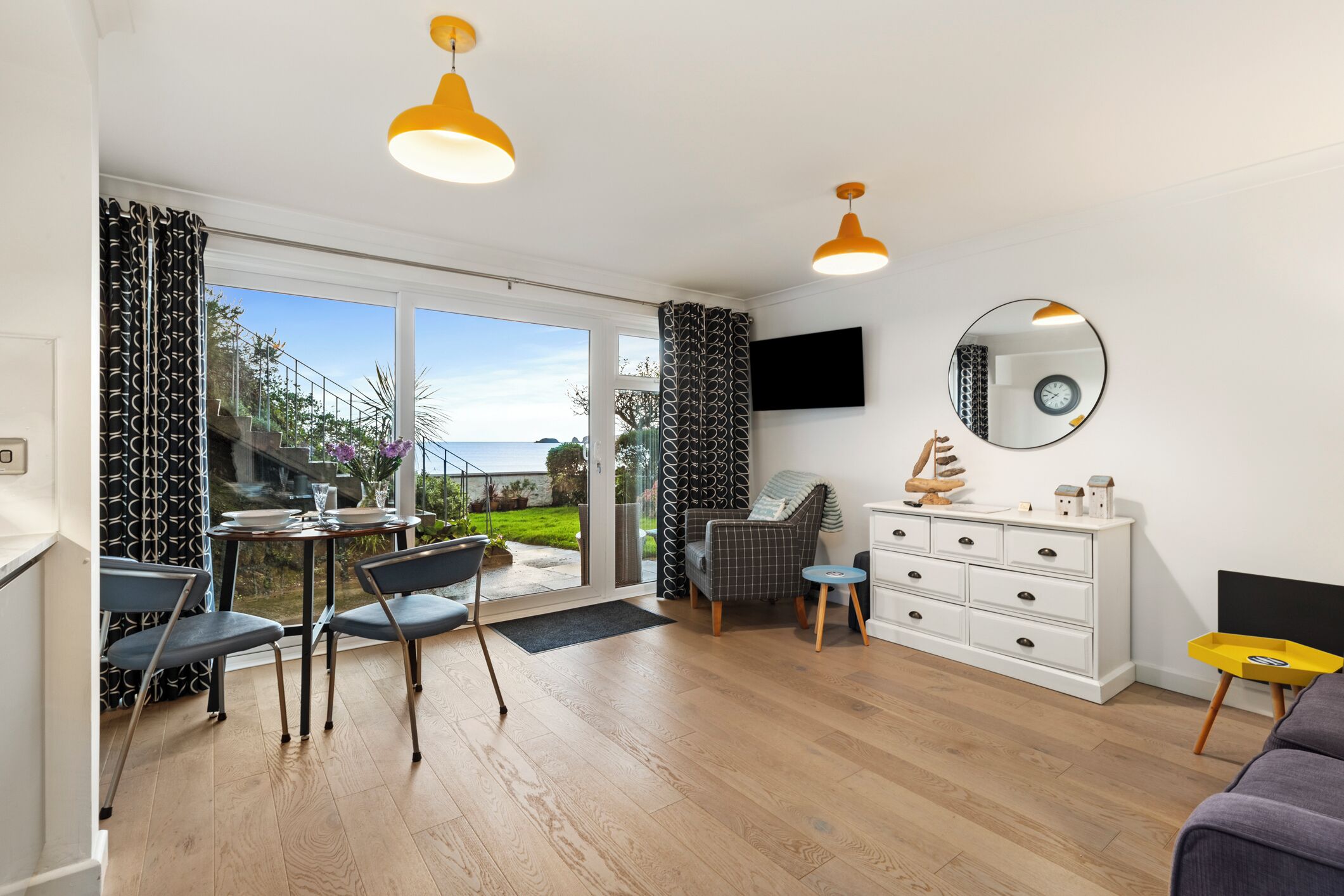 Een moderne woonkamer met een eethoek, grote ramen en uitzicht op de omgeving.