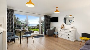 A modern living room with a dining area, large windows, and a view of the outdoors. - 2 Beach Court - Direct Beach Access, Sea Views (Saundersfoot)