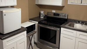 A compact kitchen with white cabinets, a built-in microwave, a stove, and a sink. - Marvelous basement apartment with WiFi in Elmont (Elmont)