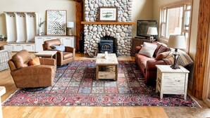A cozy living room with a stone fireplace, leather sofas, a coffee table, and a large rug. - Fabulous cottage suite, spectacular Stoney Lake view! (Douro-Dummer)