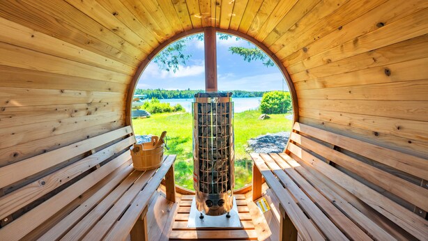 A wooden cabin with a large arched window, a central fireplace, and wooden benches.