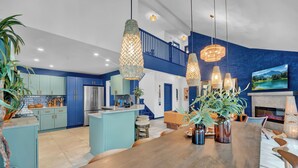 A modern kitchen with blue cabinets, a wooden island, and hanging pendant lights.