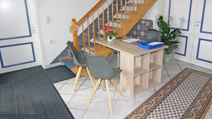 Ein kleiner Raum mit Schreibtisch, zwei Stühlen, einer Pflanze und einer Treppe.