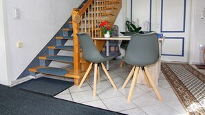 Eine Treppe mit Holzstufen und einem Geländer, die zu einem Raum mit einem Esstisch, zwei Stühlen und einer Vase mit Blumen führt.