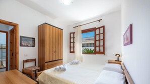 Un dormitorio con cama, armario de madera, escritorio y silla.