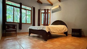 A bedroom with a bed, a chair, and a window with curtains. - Congo House (Provincia de Guanacaste)