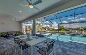 A spacious indoor area with a pool, a ceiling fan, and a view of the outdoors. - Spacious 4-bedroom house in beautiful Cape Coral with WiFi, AC, Dock, Pool, Spa (Cape Coral)