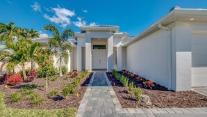 A modern building with a central entrance, surrounded by landscaped gardens and palm trees. - Spacious 4-bedroom house in beautiful Cape Coral with WiFi, AC, Dock, Pool, Spa (Cape Coral)