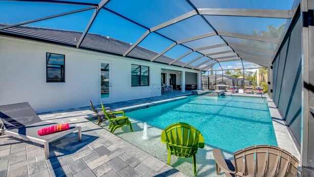A covered swimming pool with lounge chairs and a patio area. - Spacious 4-bedroom house in beautiful Cape Coral with WiFi, AC, Dock, Pool, Spa (Cape Coral)