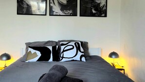 A bedroom with a bed, pillows, and a nightstand with a lamp. - L'Atelier-T2 near the Wifi-Parking center (Lourdes)