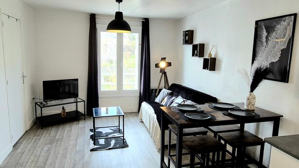 A modern living room with a sofa, dining table, and a TV. - L'Atelier-T2 near the Wifi-Parking center (Lourdes)