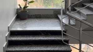 Eine Treppe mit Granitschritten führt zu einem Zwischenpodest, auf dem ein Blumentopf steht, und durch ein großes Fenster ist eine Stadtansicht zu sehen.