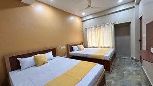 Ein Hotelzimmer mit zwei Betten, einem Deckenventilator und einer Badezimmertür.