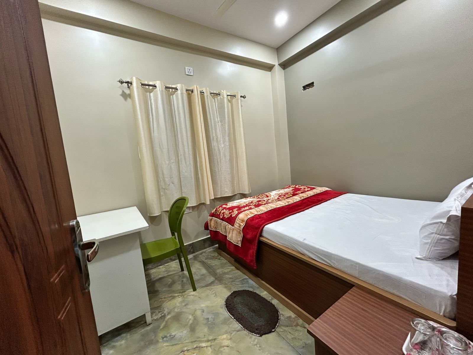 A bedroom with a bed, a desk, and a chair.