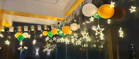 Une pièce dotée d’une grande fenêtre, décorée de guirlandes lumineuses en forme d’étoiles et de ballons.