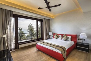 A modern hotel room with a large bed, a ceiling fan, a nightstand, and a view of the outdoors.