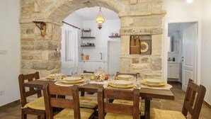 A dining area with a stone archway, wooden chairs, and a table set for six. - Holiday Home Marilu with pool (Stankovci)