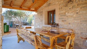 An outdoor wooden table with benches, a stone wall, and a window. - Holiday Home Marilu with pool (Stankovci)