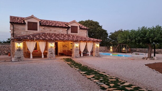 A stone house with a tiled roof, a swimming pool, and a garden path. - Holiday Home Marilu with pool (Stankovci)