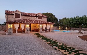 A stone house with a tiled roof, a swimming pool, and a garden path. - Holiday Home Marilu with pool (Stankovci)