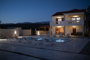 Une maison à deux étages avec une piscine et un espace extérieur aménagé pour se détendre.