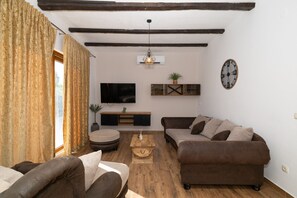 A living room with a sofa set, a coffee table, a TV, and a clock on the wall. - Zen Garden Villa with heated pool (Posedarje)