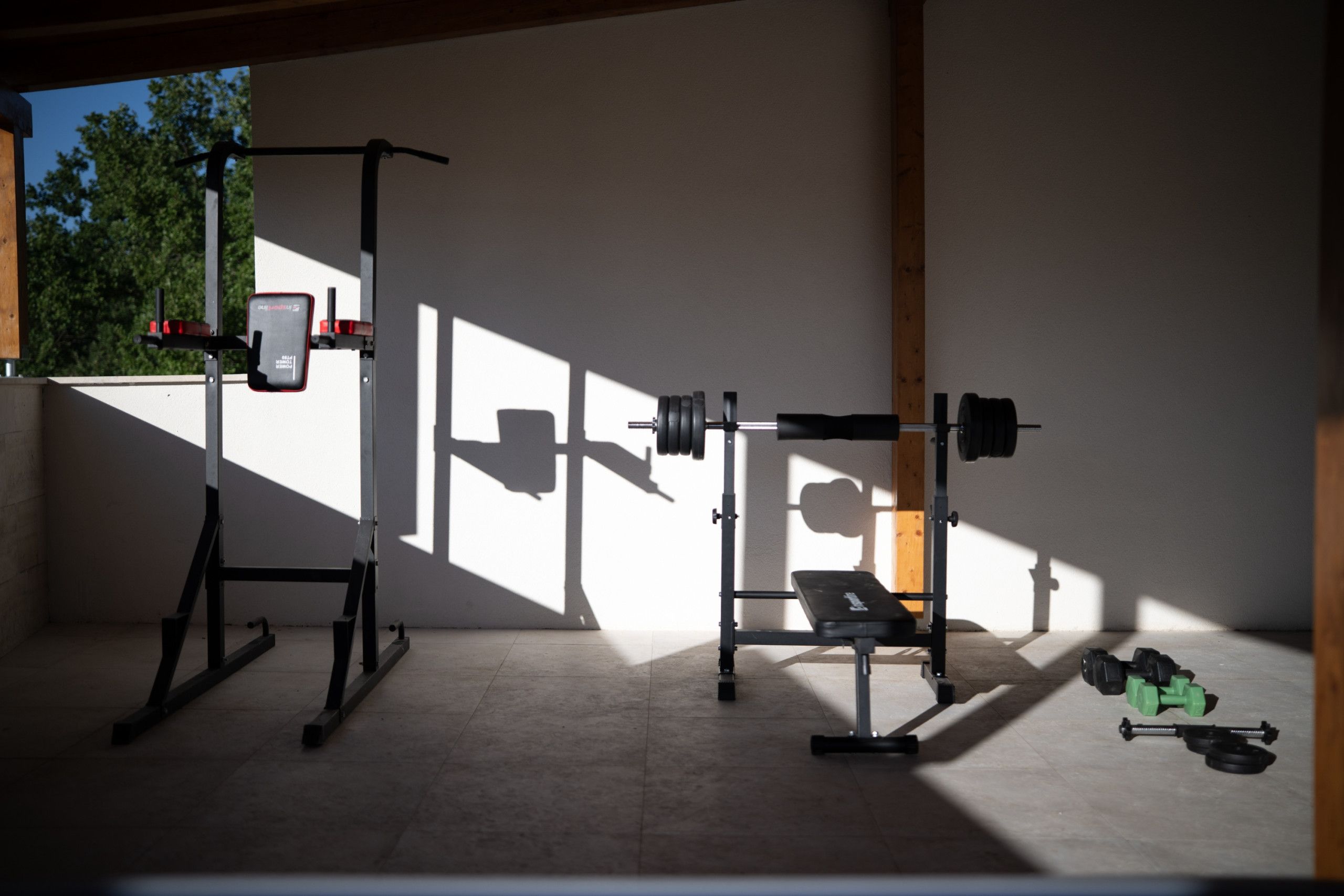 A gym with exercise equipment including a bench, squat rack, and dumbbells.