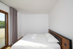 A hotel room with a bed, a window with curtains, and a view of greenery outside. - Zen Garden Villa with heated pool (Posedarje)