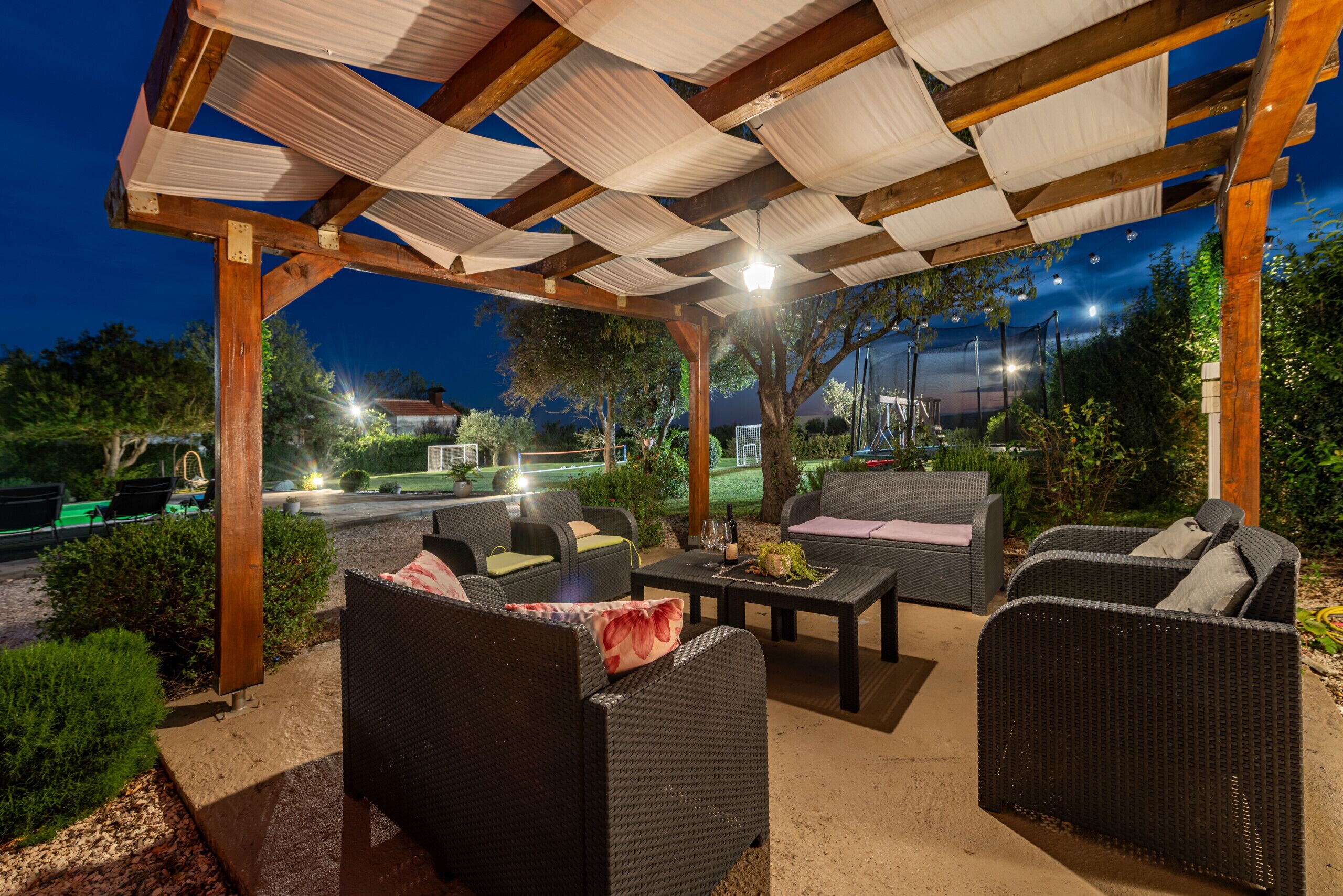 Un espace extérieur aménagé en terrasse, avec des meubles en osier, une table avec des boissons et un coin salon abrité.