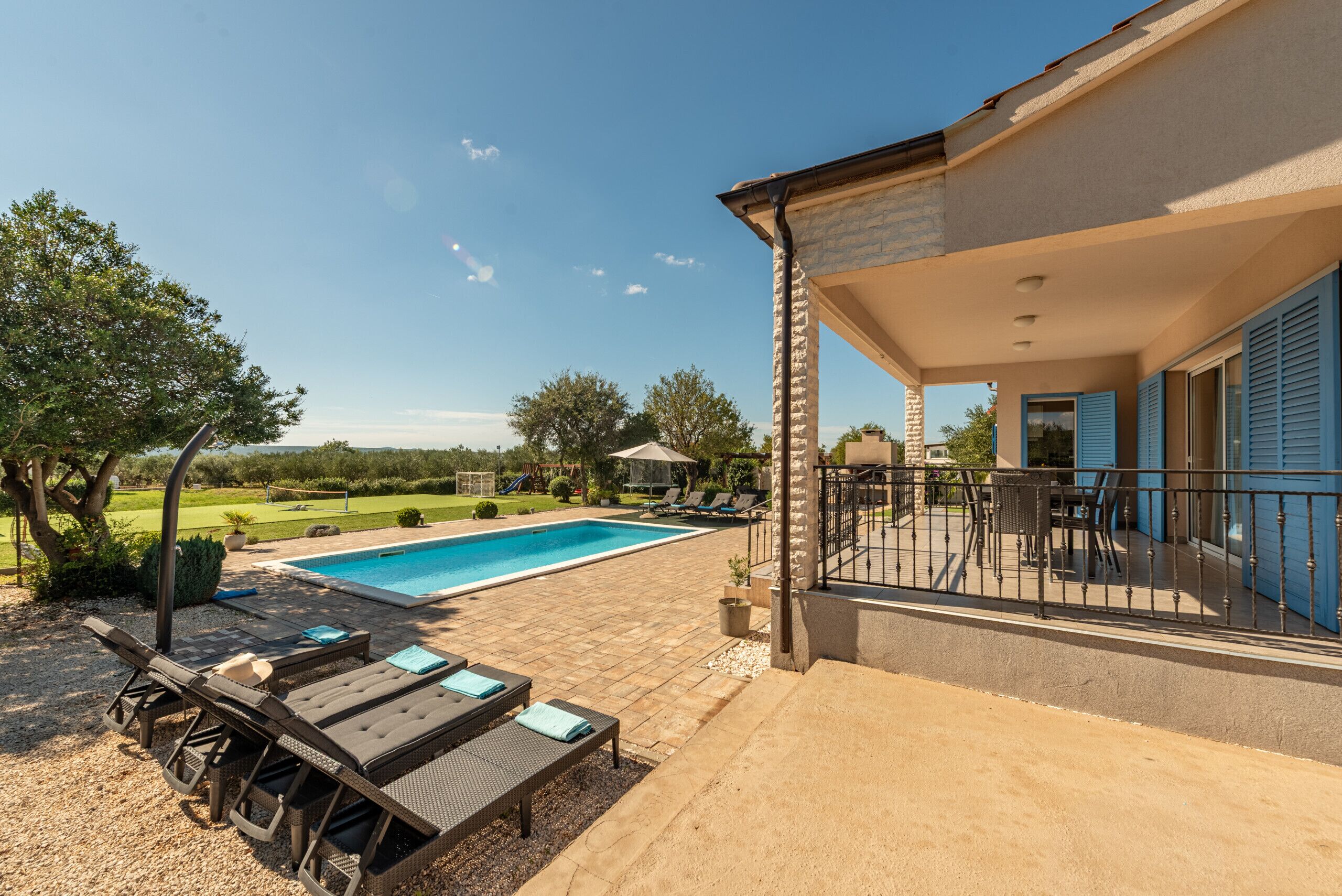 A poolside area with lounge chairs, a table, and a covered seating area with a view of the pool and surrounding landscape.
