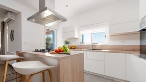 Une cuisine moderne dotée d’un îlot central, de meubles blancs et d’une hotte en acier inoxydable.
