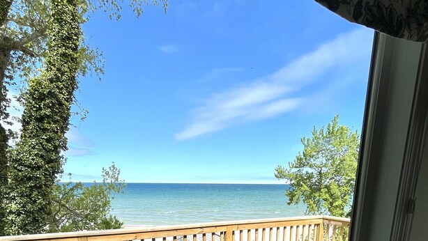 Un balcon avec vue sur la mer, deux chaises et une petite table.