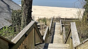 Une promenade en bois mène à une plage de sable, d’où l’on a une vue dégagée sur l’océan.