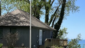 Un petit bâtiment d’un seul étage, doté d’un toit en pente, d’un porche à l’avant et offrant une vue sur une étendue d’eau.