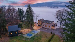 A two-story house with a tennis court, surrounded by trees and a lake. - Riverside Retreat  Sleeps 20 (Halifax)