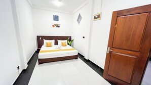 A hotel room with a bed, a wooden wardrobe, a ceiling fan, and a small window. - Galle Nature Nook (Galle)
