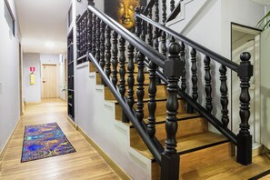 A staircase with black balusters and a wooden handrail, leading to a landing with a door marked '3'. - Hotel Casa 73 Deluxe (Medellín)