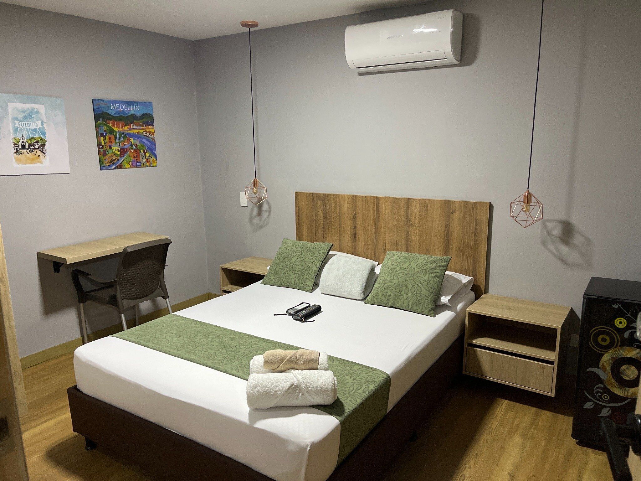 Une chambre d’hôtel bien aménagée, avec un lit, des tables de chevet, un bureau et un appareil de climatisation.