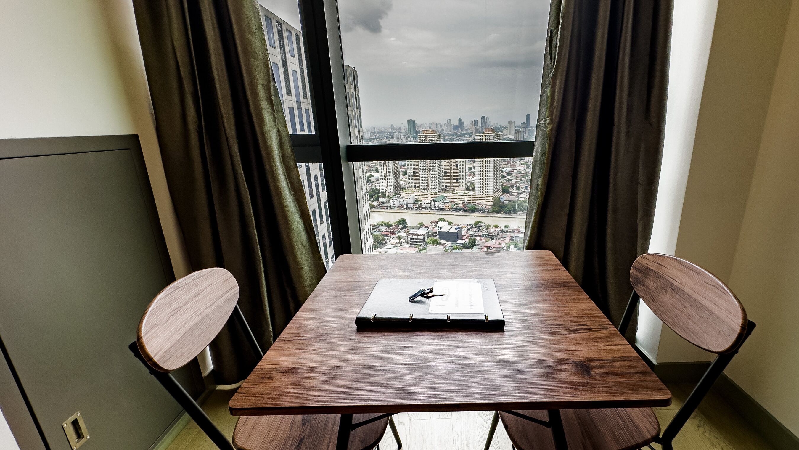A small dining area with a table and two chairs, a notebook, and a pen on the table.