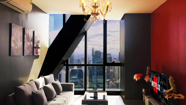 A modern living room with a city view, a staircase, and a large window. - Century Spire (Makati)
