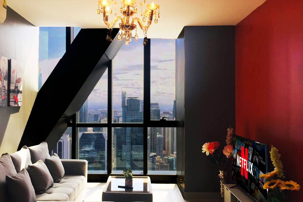 A modern living room with a city view, a staircase, and a large window.