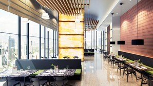 A modern restaurant with high ceilings, large windows, and a city view. Tables are set with green tablecloths and white napkins. - Century Spire (Makati)