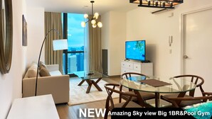 A modern living room with a glass table, a sofa, a TV, and a view of the city. - Century Spire (Makati)