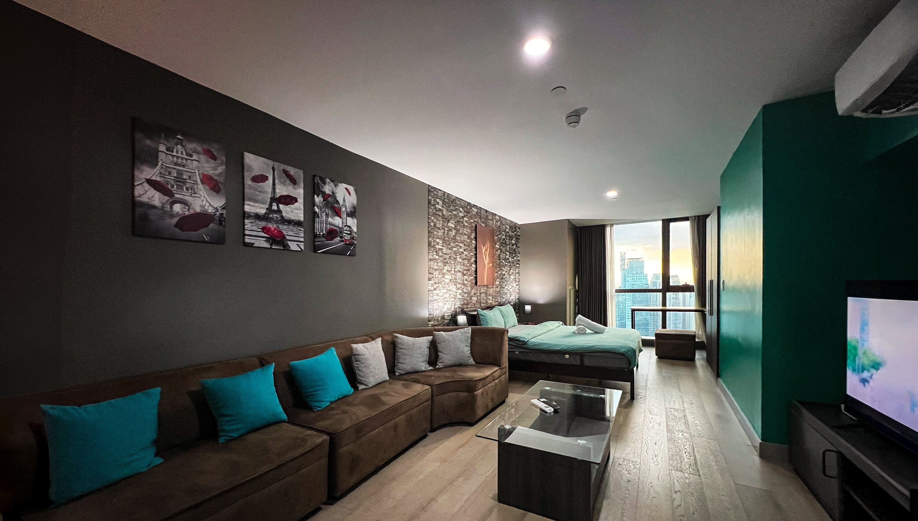 A modern living room with a sectional sofa, a glass coffee table, and a large flat-screen TV.
